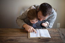 father and toddler daughter reading a Bible together 