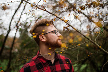 a man in a plaid flannel shirt standing outdoors 