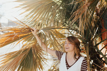 a woman holding onto a palm tree 