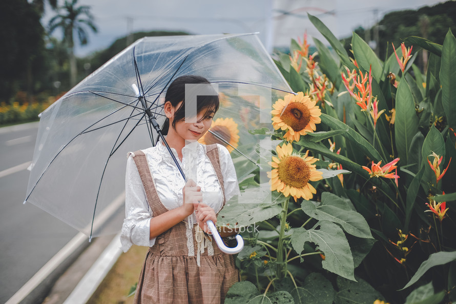 a young woman standing in a field of sunflowers holding an umbrella 