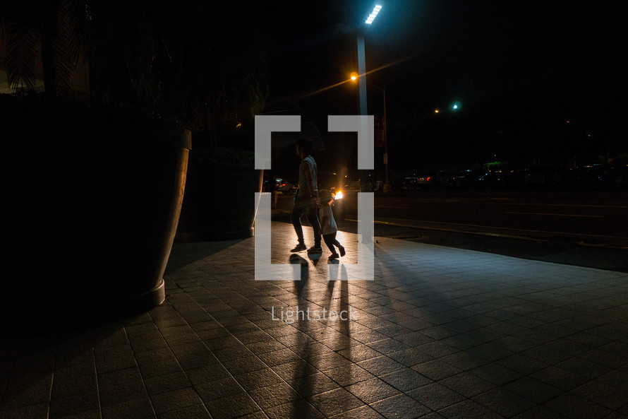father and son walking on a city sidewalk at night 