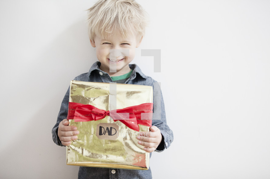 A child holding a Christmas gift for Dad