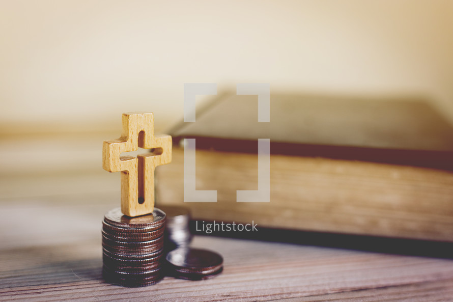 Bible, stack of coins, and cross