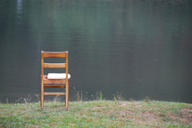 a chair sitting at the edge of a lake 