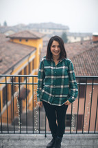 A woman in a green shirt smiling in front of a patio rail