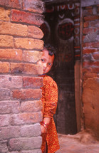 a girl peeking from around a corner 