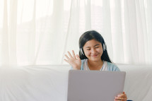 teen girl looking at a computer and waving 