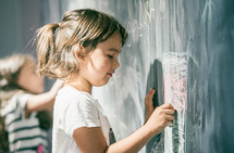 girl drawing on a blackboard at playground