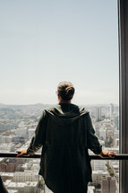 a man standing on a balcony looking out over a city 