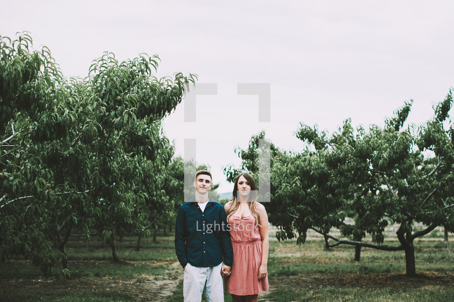 a couple in an orchard holding hands 