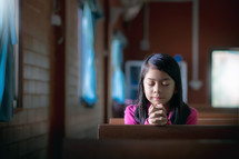 a girl praying alone in a church 