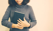 a woman holding a Bible close to her heart 