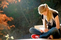 a teen girl holding a Bible with head bowed in prayer 