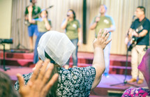 woman worshiping God, at church, with hand up.
