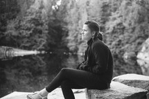 portrait of a young woman sitting on a rock outdoors 