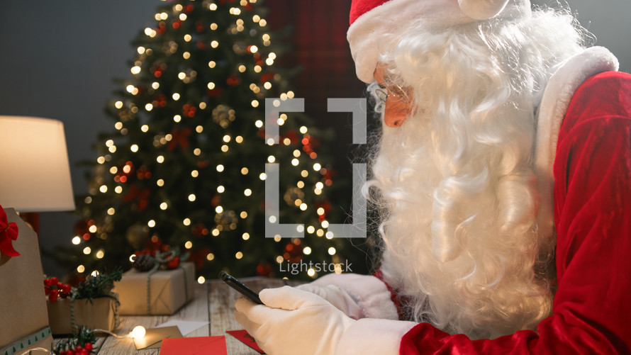 Santa chatting with smartphone under the tree