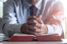 a businessman praying over an open Bible 