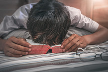 a man praying over a Bible on his bed 