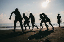silhouettes of a family running on a beach 