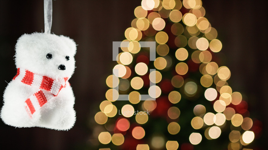 Small polar bear decoration with blurred Christmas tree