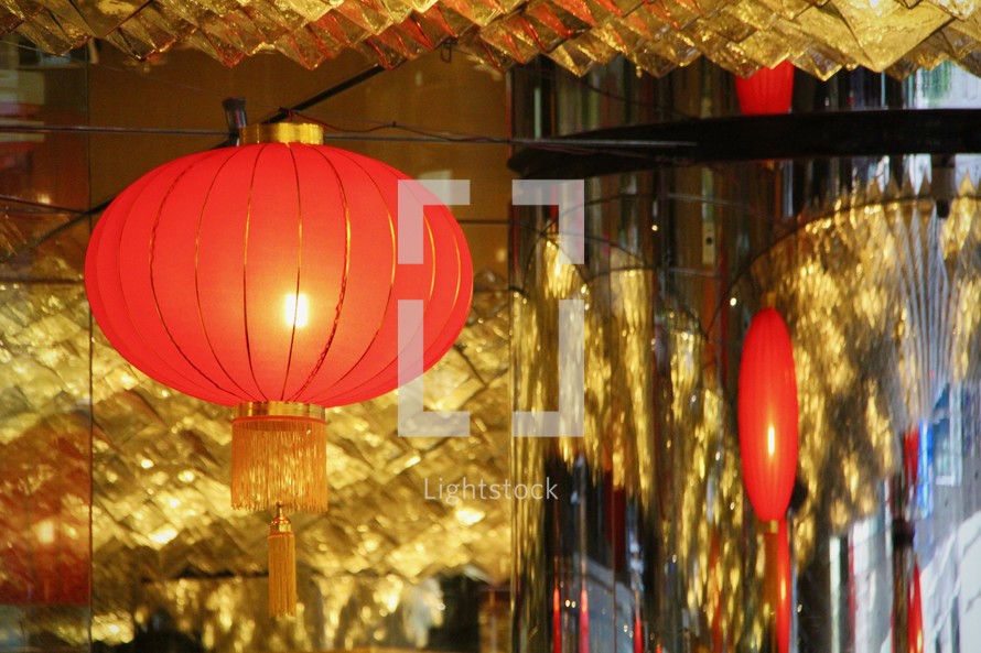 A red Chinese lunar new year lantern hanging in a gold room.