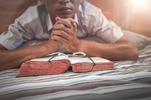 a man reading a Bible in bed 