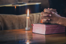 praying hands and Bible with candle 