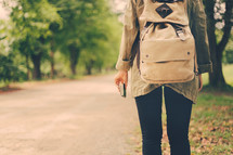 a woman with a backpack walking carrying a Bible 