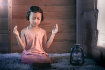 a girl praying with hands raised 