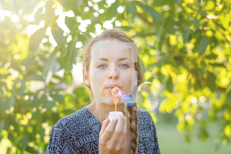 Young beautiful woman blowing bubbles 