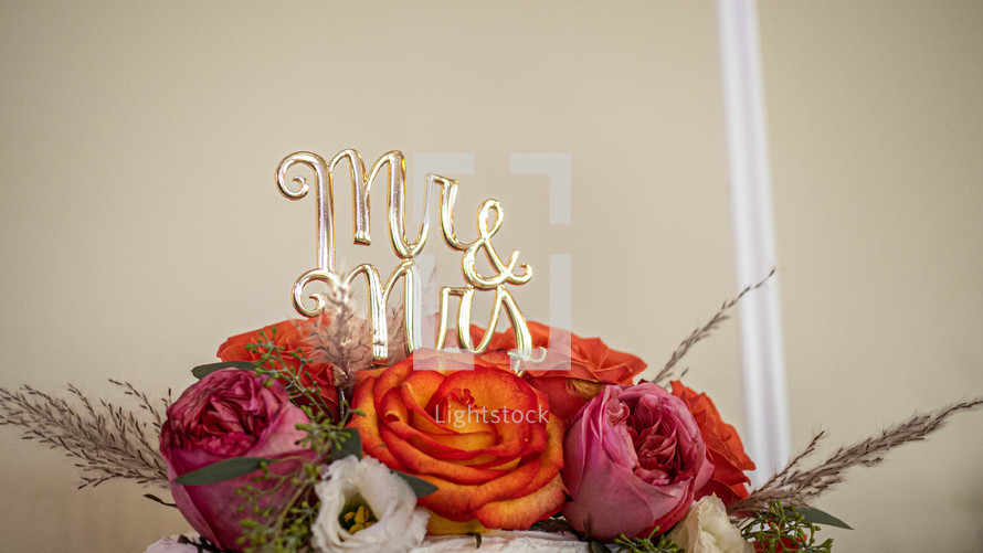 Wedding cake topper amidst floral arrangement