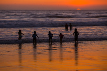children playing in the ocean at sunset 