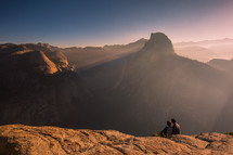 couple sitting on a mountain top under sunlight 