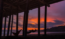 hammocks under a pier at sunset 