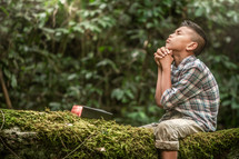 a boy sitting in a tree praying 