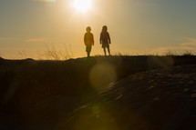 silhouettes of children standing on top of a hill 