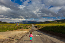 toddler girl walking down a rural road 