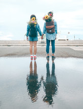couple with flowers in a backpack standing on a beach 