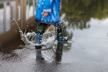a child in rain boots splashing in puddles 
