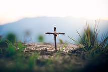 cross in the ground with mountains in the background 