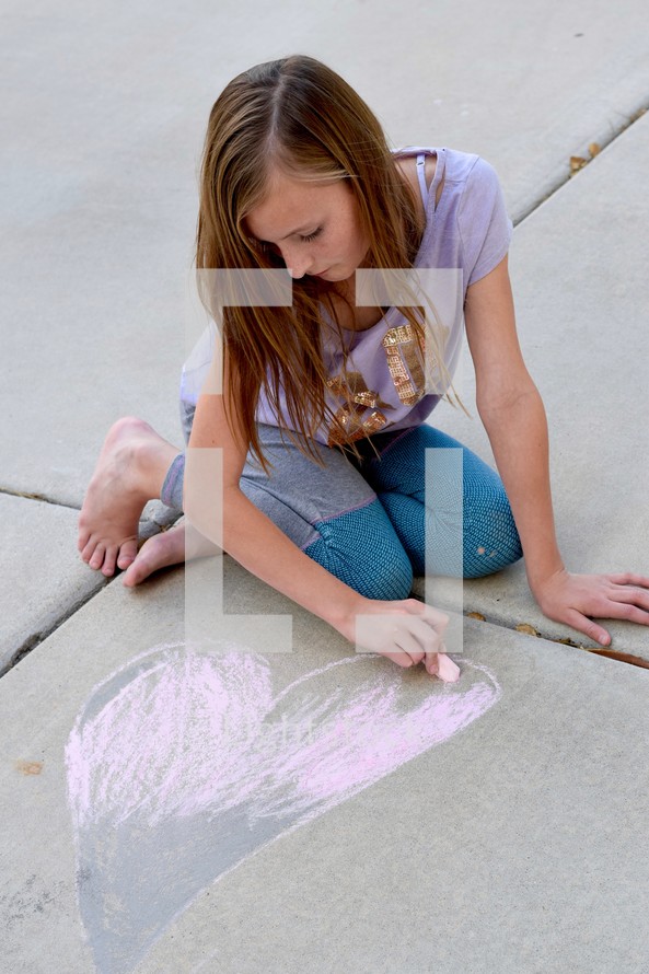 girl drawing a heart on a sidewalk 