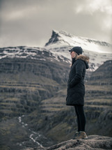 a woman standing on a rock looking out 