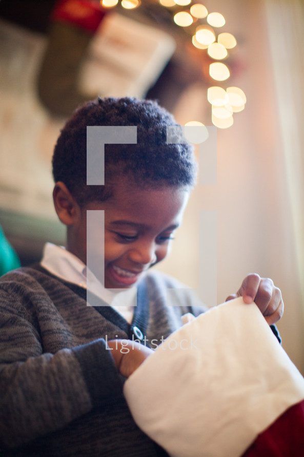 African American toddler boy looking in a Christmas stocking 