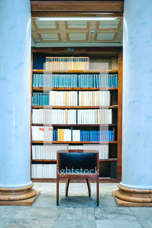 a chair in front of books on a bookshelf in a library 