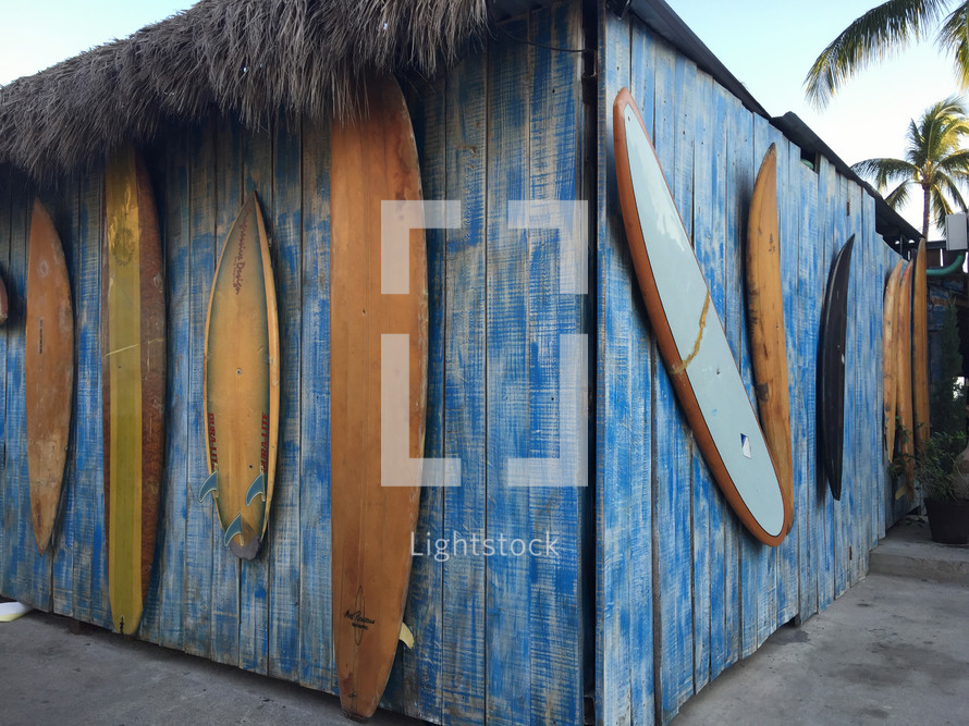 surfboards on the side of a shack 