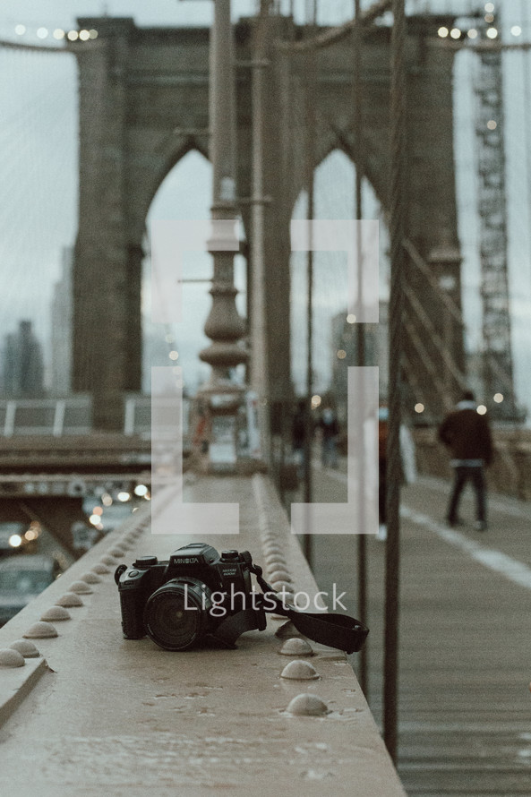camera sitting on a railing of a bridge in New York City 