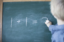 A child doing math on a chalk board.
