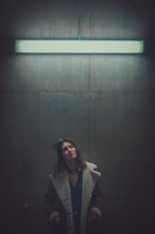 a woman standing under a florescent lights 