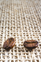 Close up from a few coffee beans laying down on a Burlap fabric background. Background voor coffee related products.
