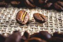 Close up from a few coffee beans laying down on a Burlap fabric background. Background voor coffee related products.
